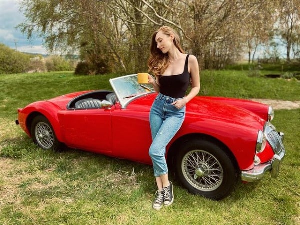 Picture of Najarra Townsend sitting on her favorite MG MGA car of color red.